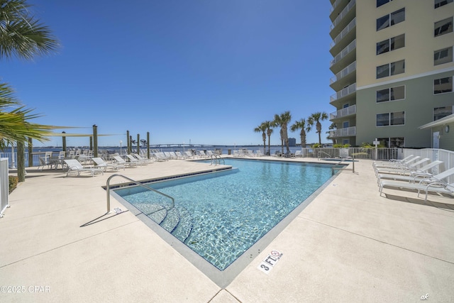 community pool with a patio area and fence