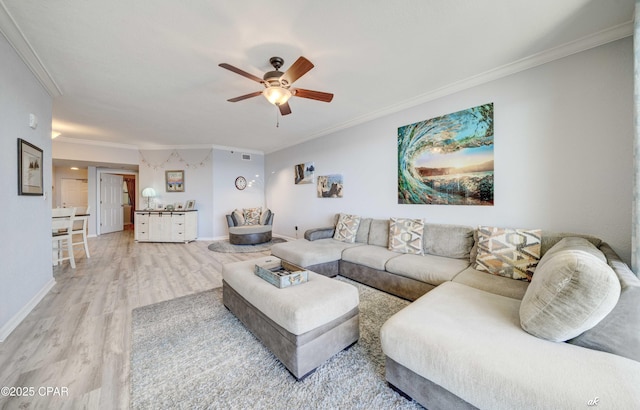 living room featuring baseboards, light wood-type flooring, a ceiling fan, and ornamental molding