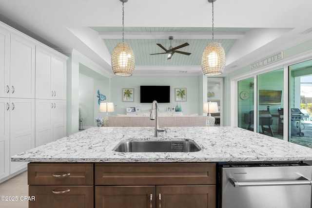 kitchen featuring light stone countertops, a sink, hanging light fixtures, white cabinetry, and open floor plan