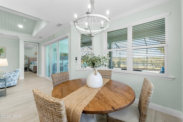 dining room featuring light wood finished floors, visible vents, baseboards, a chandelier, and ornamental molding