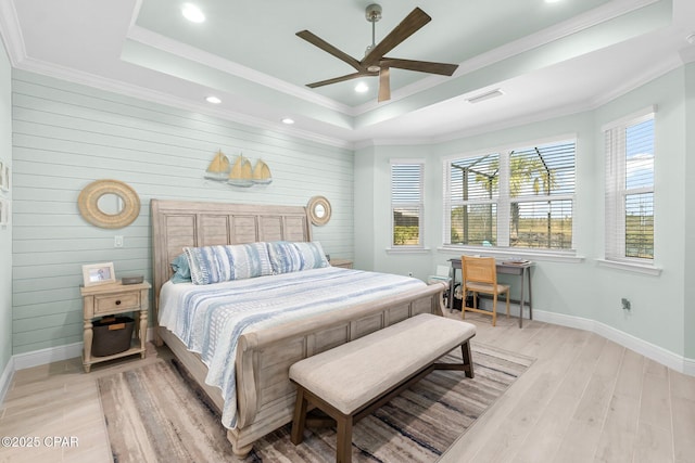 bedroom with a raised ceiling, light wood-style flooring, visible vents, and ornamental molding