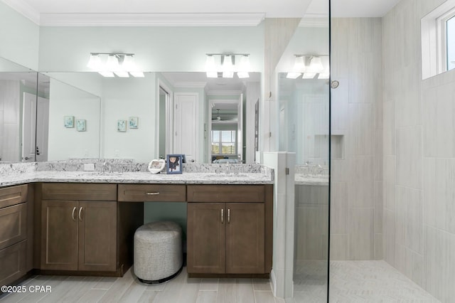 bathroom with a sink, double vanity, a walk in shower, and ornamental molding