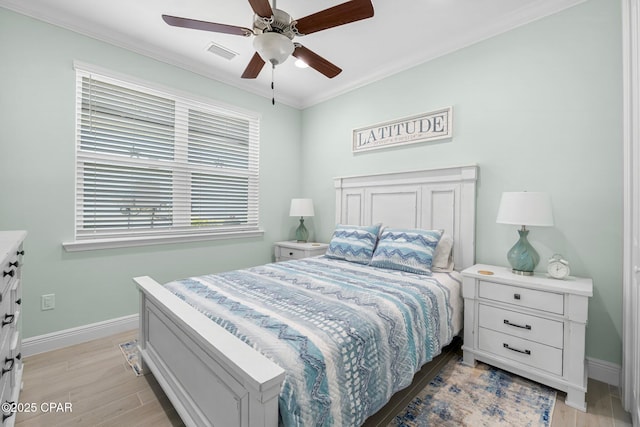 bedroom with light wood-style floors, baseboards, visible vents, and ornamental molding