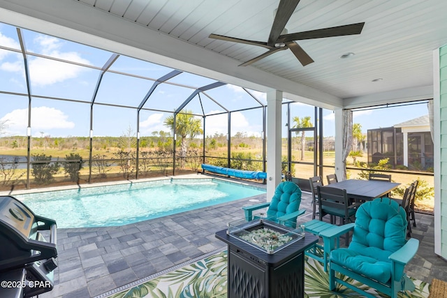 view of pool featuring a ceiling fan, a covered pool, an outdoor fire pit, glass enclosure, and a patio area