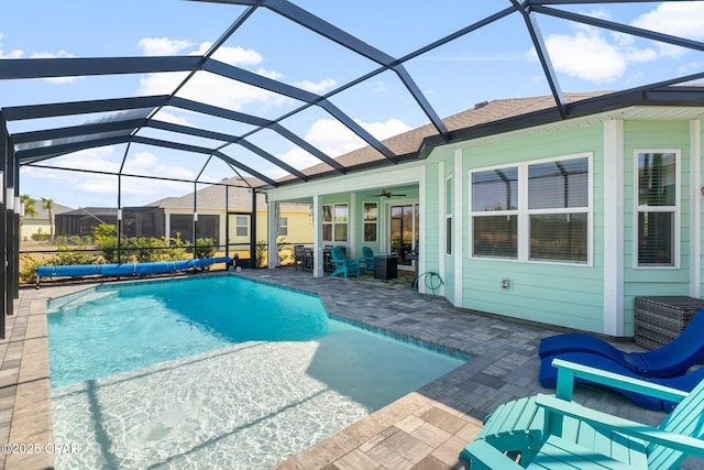 view of swimming pool featuring a covered pool, a patio, ceiling fan, and glass enclosure