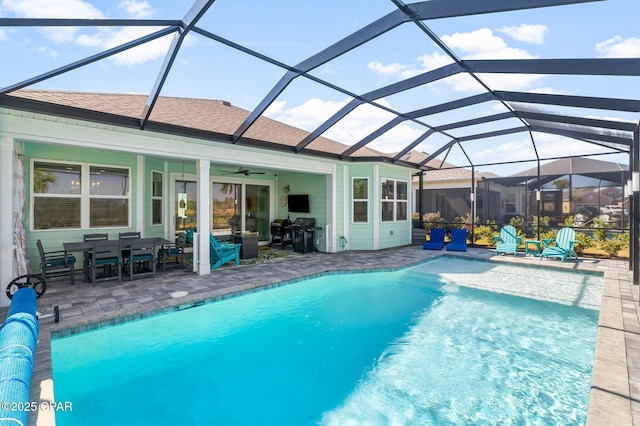 outdoor pool featuring glass enclosure, a patio, and a ceiling fan