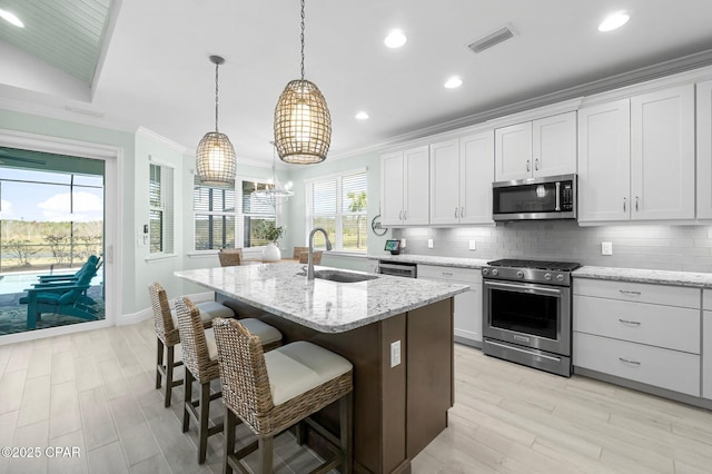 kitchen featuring decorative backsplash, visible vents, appliances with stainless steel finishes, and a sink