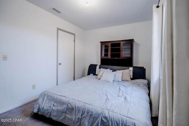 carpeted bedroom featuring visible vents, baseboards, and a textured ceiling