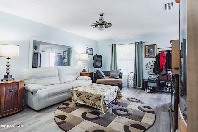 living room with light wood-style flooring, visible vents, and ceiling fan