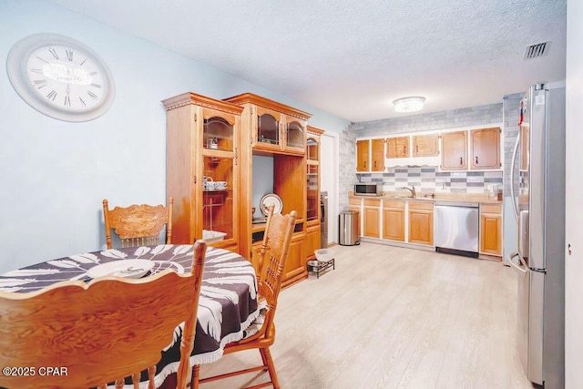 dining space featuring light wood-style flooring, visible vents, and a textured ceiling