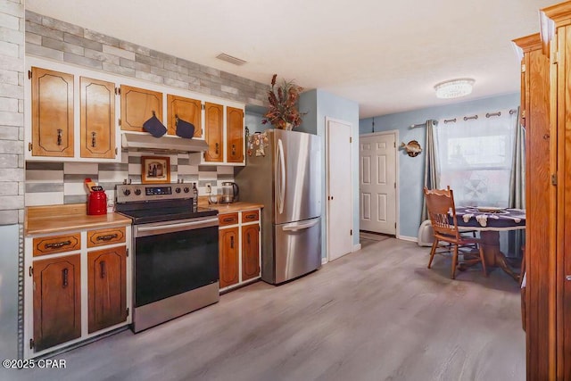 kitchen featuring visible vents, light wood-style flooring, light countertops, under cabinet range hood, and appliances with stainless steel finishes