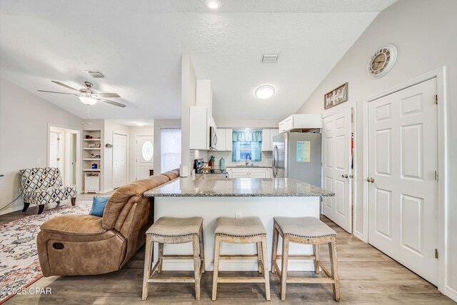 1705 Rhett Pl, Lynn Haven, FL 32444 - kitchen with appliances with stainless steel finishes, a peninsula, vaulted ceiling, white cabinetry, and a breakfast bar