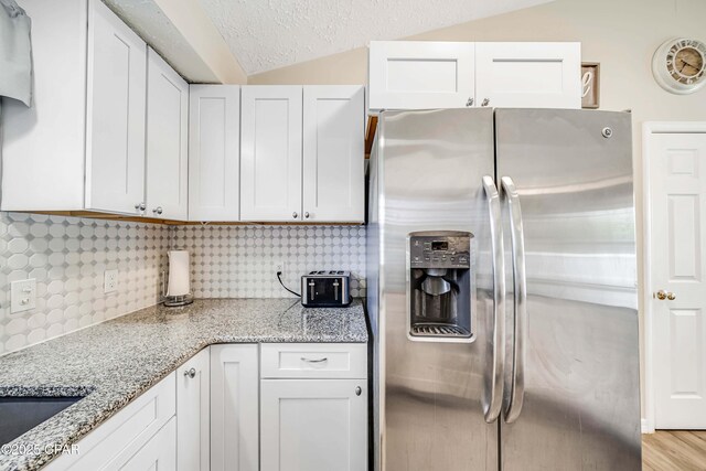 1705 Rhett Pl, Lynn Haven, FL 32444 - kitchen with stainless steel fridge with ice dispenser, white cabinetry, backsplash, and lofted ceiling