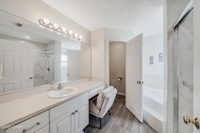 1705 Rhett Pl, Lynn Haven, FL 32444 - bathroom with a marble finish shower, a garden tub, wood finished floors, vanity, and a textured ceiling