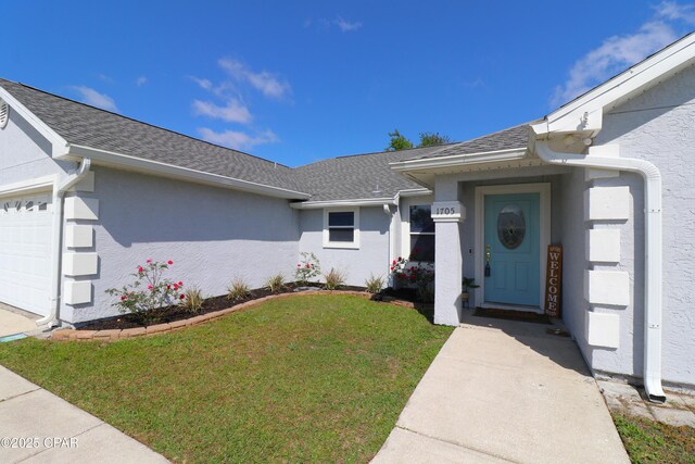 entrance to property featuring stucco siding, a yard, and roof with shingles