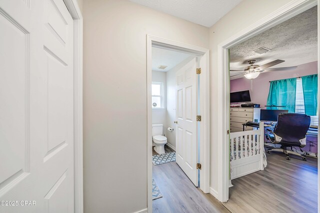 1705 Rhett Pl, Lynn Haven, FL 32444 - hallway featuring light wood-style flooring, a desk, a textured ceiling, and baseboards