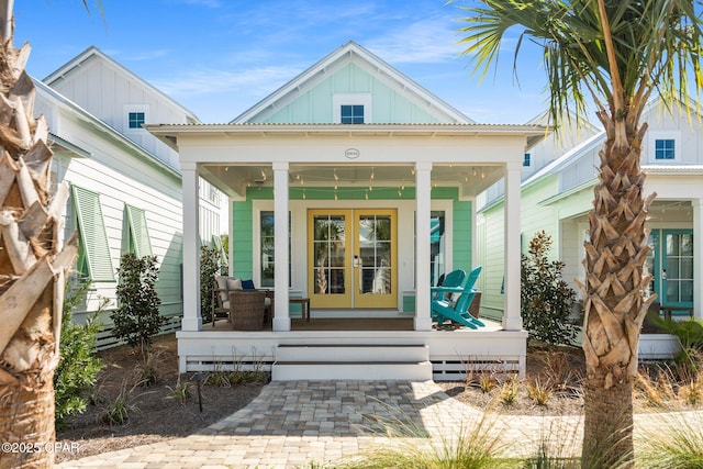 view of front facade with board and batten siding, french doors, and covered porch