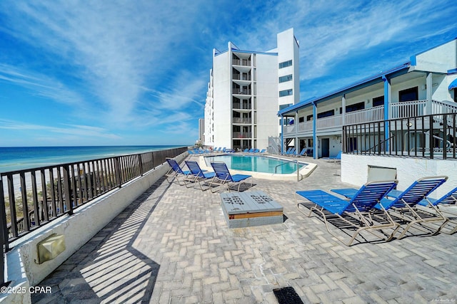 pool featuring a patio area, a beach view, and a water view