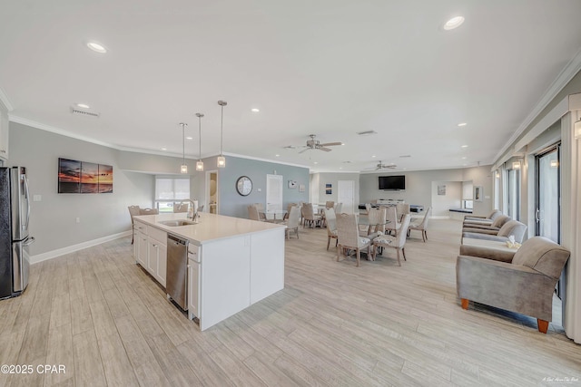 kitchen with a sink, light wood-style floors, appliances with stainless steel finishes, white cabinetry, and open floor plan