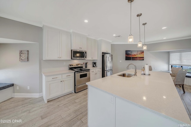 kitchen featuring ornamental molding, appliances with stainless steel finishes, light wood-style floors, white cabinetry, and a sink