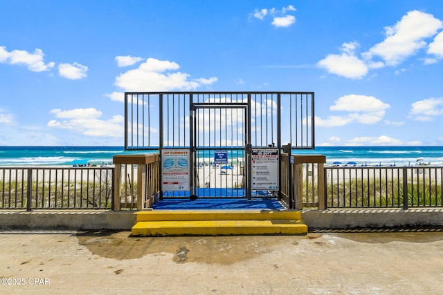 surrounding community featuring a water view, fence, and a beach view