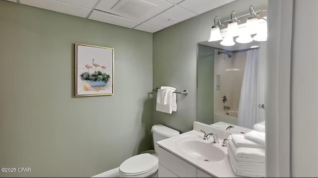 bathroom featuring vanity, baseboards, a drop ceiling, shower / tub combo, and toilet