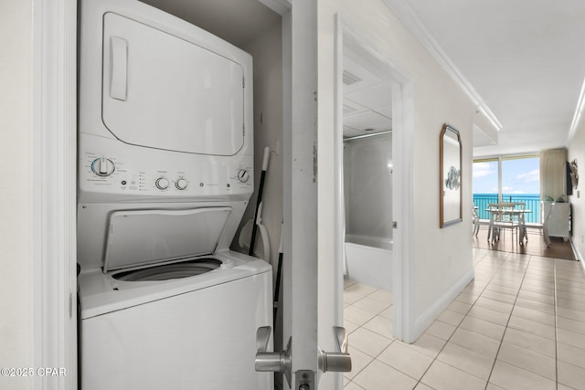 14701 Front Beach Rd Unit 1934, Panama City Beach, FL 32413 - laundry area with baseboards, ornamental molding, stacked washing maching and dryer, and light tile patterned floors