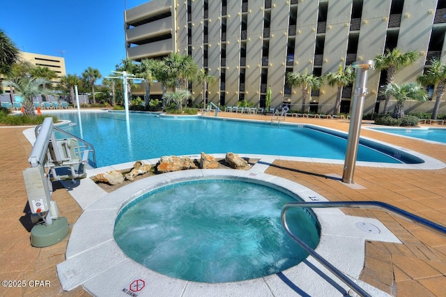 pool featuring a community hot tub and fence