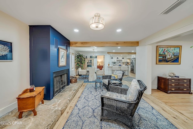 living area featuring light wood-type flooring, visible vents, a fireplace, and recessed lighting