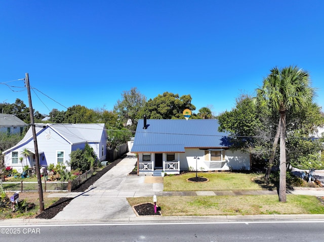 bungalow featuring metal roof, driveway, a porch, and a front yard