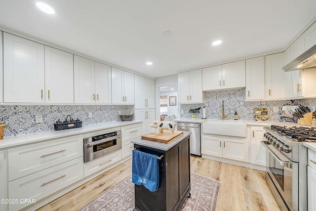 kitchen with stainless steel appliances, a sink, light countertops, and light wood-style floors