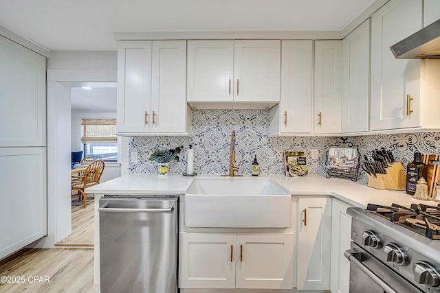 kitchen featuring a sink, extractor fan, stainless steel appliances, light countertops, and backsplash