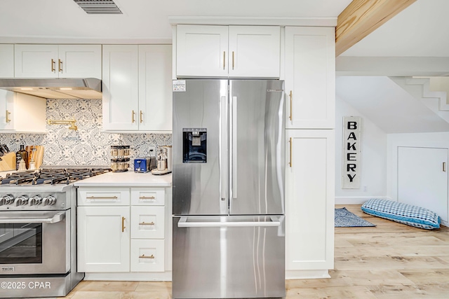 kitchen featuring visible vents, white cabinets, stainless steel appliances, under cabinet range hood, and backsplash