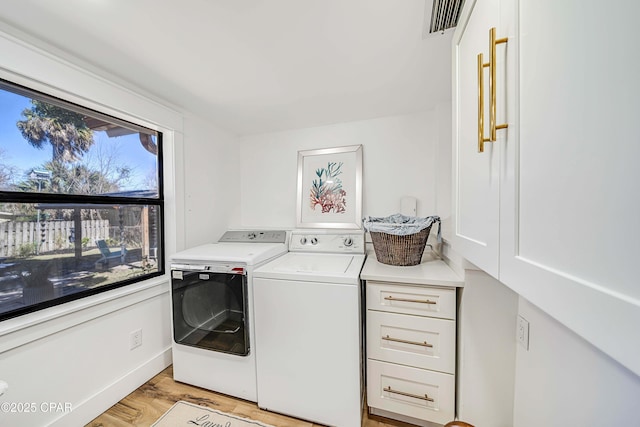 washroom with washing machine and dryer, baseboards, visible vents, and light wood finished floors