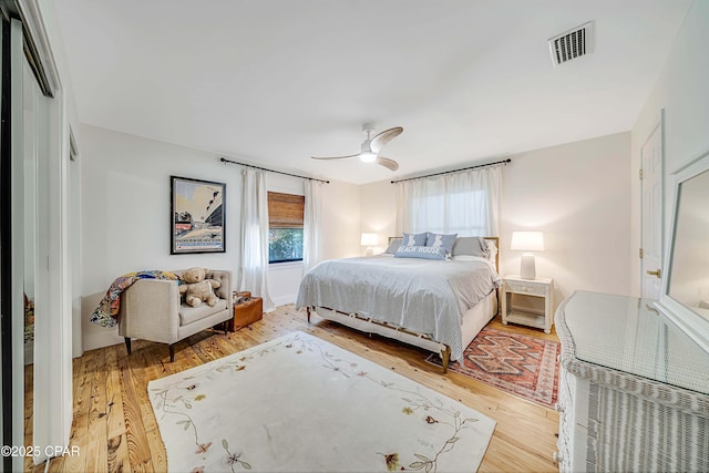 bedroom with a ceiling fan, visible vents, and wood finished floors