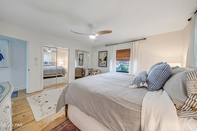 bedroom with ceiling fan, light wood-style flooring, baseboards, and two closets