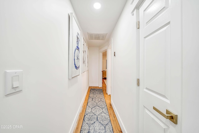 hallway with baseboards, visible vents, and light wood-style floors