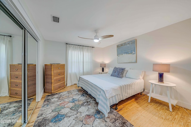 bedroom with a closet, visible vents, a ceiling fan, light wood-type flooring, and baseboards