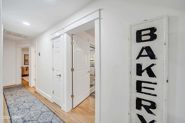 hallway featuring light wood-style floors, recessed lighting, visible vents, and baseboards