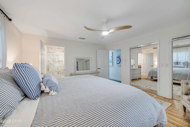 bedroom featuring ceiling fan, multiple closets, visible vents, and light wood-style floors