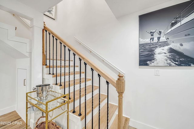 staircase featuring baseboards and wood finished floors