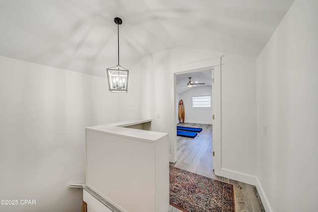 hall featuring lofted ceiling, baseboards, and wood finished floors