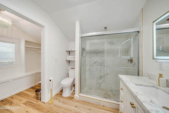 full bathroom with toilet, vanity, a marble finish shower, and wood finished floors