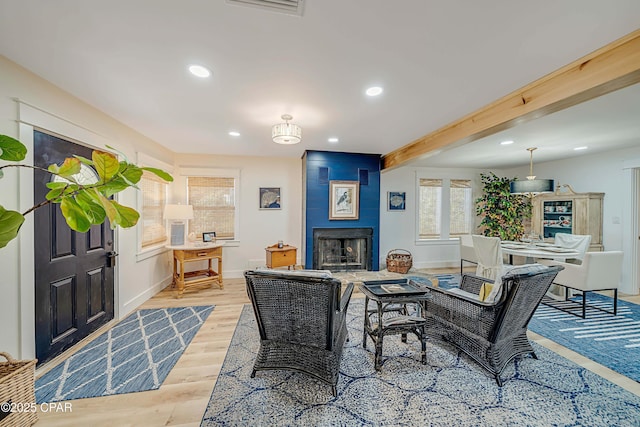 interior space featuring recessed lighting, a large fireplace, wood finished floors, beamed ceiling, and baseboards