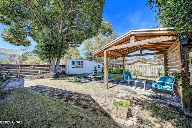 view of yard featuring a patio area, a fenced backyard, and an outdoor structure