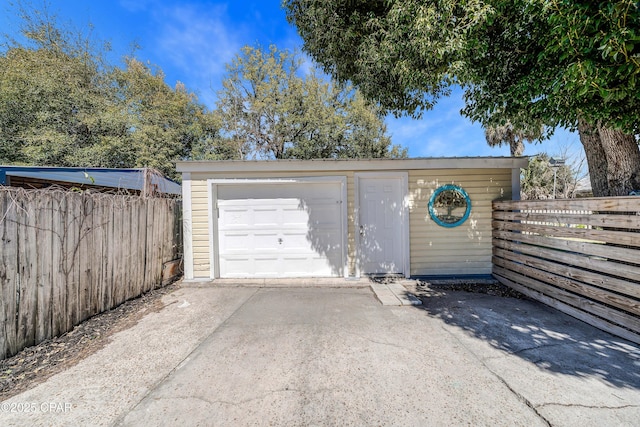 detached garage with fence and concrete driveway