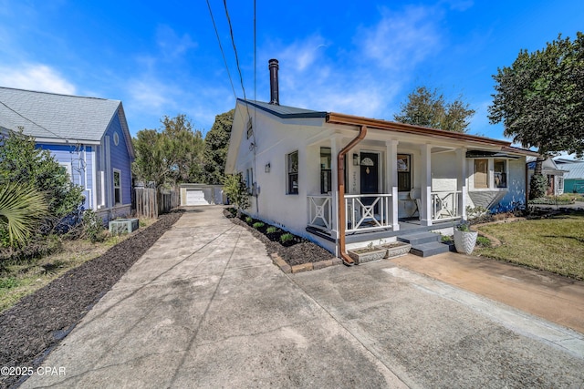 view of front of house featuring a garage, an outbuilding, a porch, and stucco siding