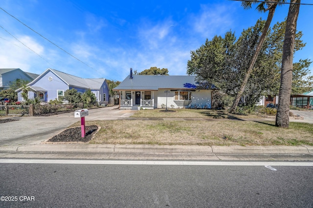 view of front of property featuring driveway, metal roof, a porch, and a front yard