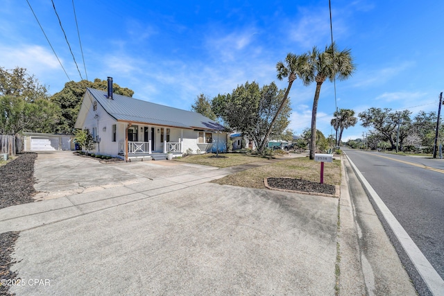 view of front of home with a garage, metal roof, and a porch