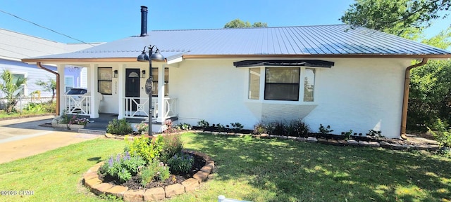 view of front of house featuring a porch, a front yard, metal roof, and stucco siding